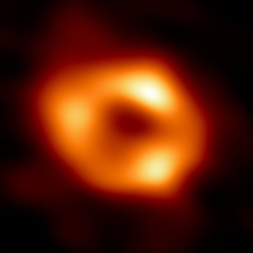 Primera imagen obtenida de Sagitario A*, el agujero negro encontrado en el centro de la Vía Láctea. El equipo internacional del Telescopio del Horizonte de Eventos (EHT) fue capaz de obtener esta imagen combinando las observaciones de radiotelescopios (capaces de captar ondas de radio) repartidos por todo el mundo, sincronizándolos para que funcionaran como un solo equipo. Lo que se ve realmente del agujero negro es su sombra, rodeada de un anillo luminoso generado por el material que orbita a su alrededor. Algunos fotones caen en su interior, pero otros son desviados por la atracción generada, dibujando la silueta que se observa en la imagen. Fuente: Event Horizon Telescope (EHT)